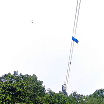 送電線に引っ掛かったシート（訓練）をドローンで空撮する様子
